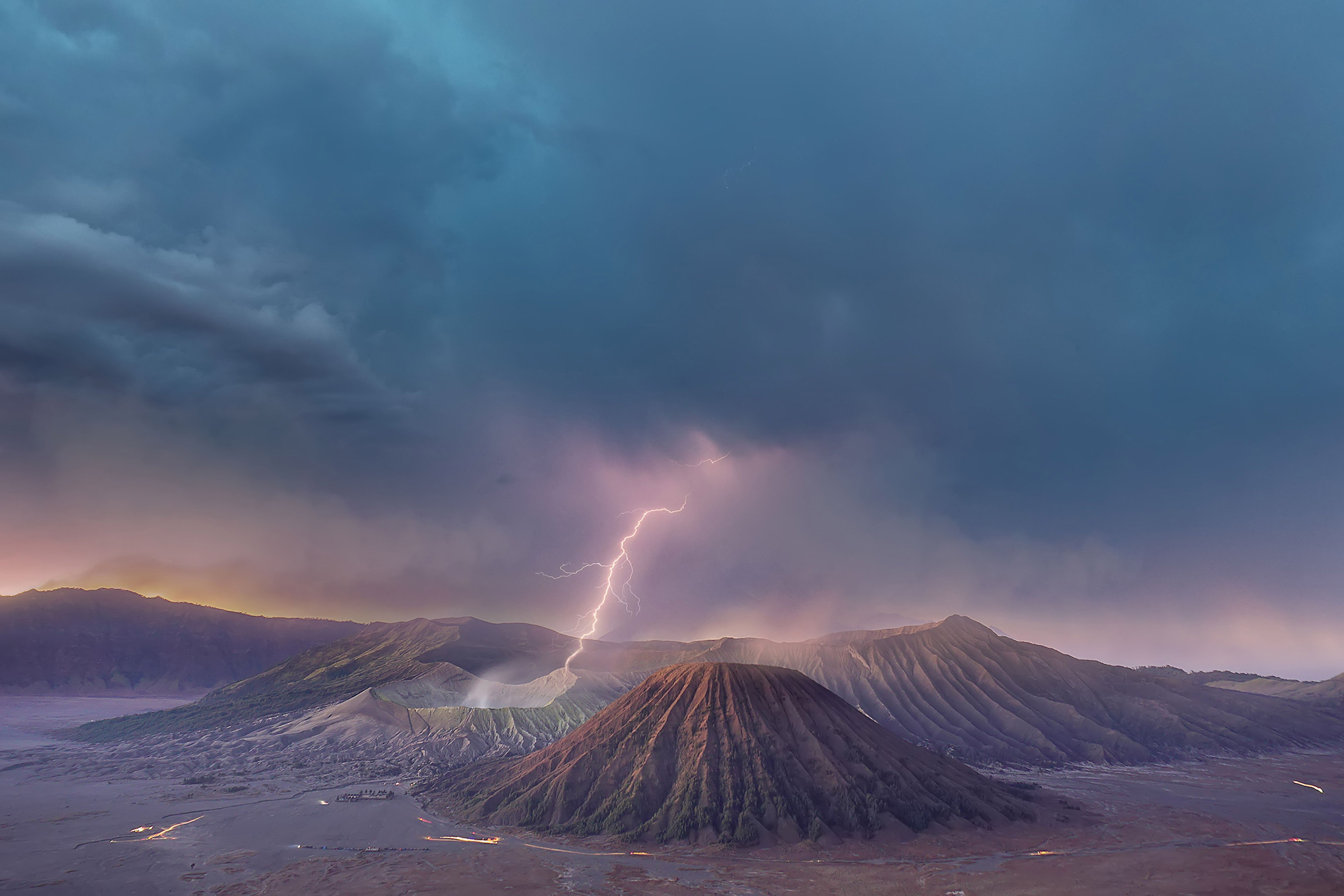 A lightning bolt flashes above a volcanic landscape under thick, heavy clouds.