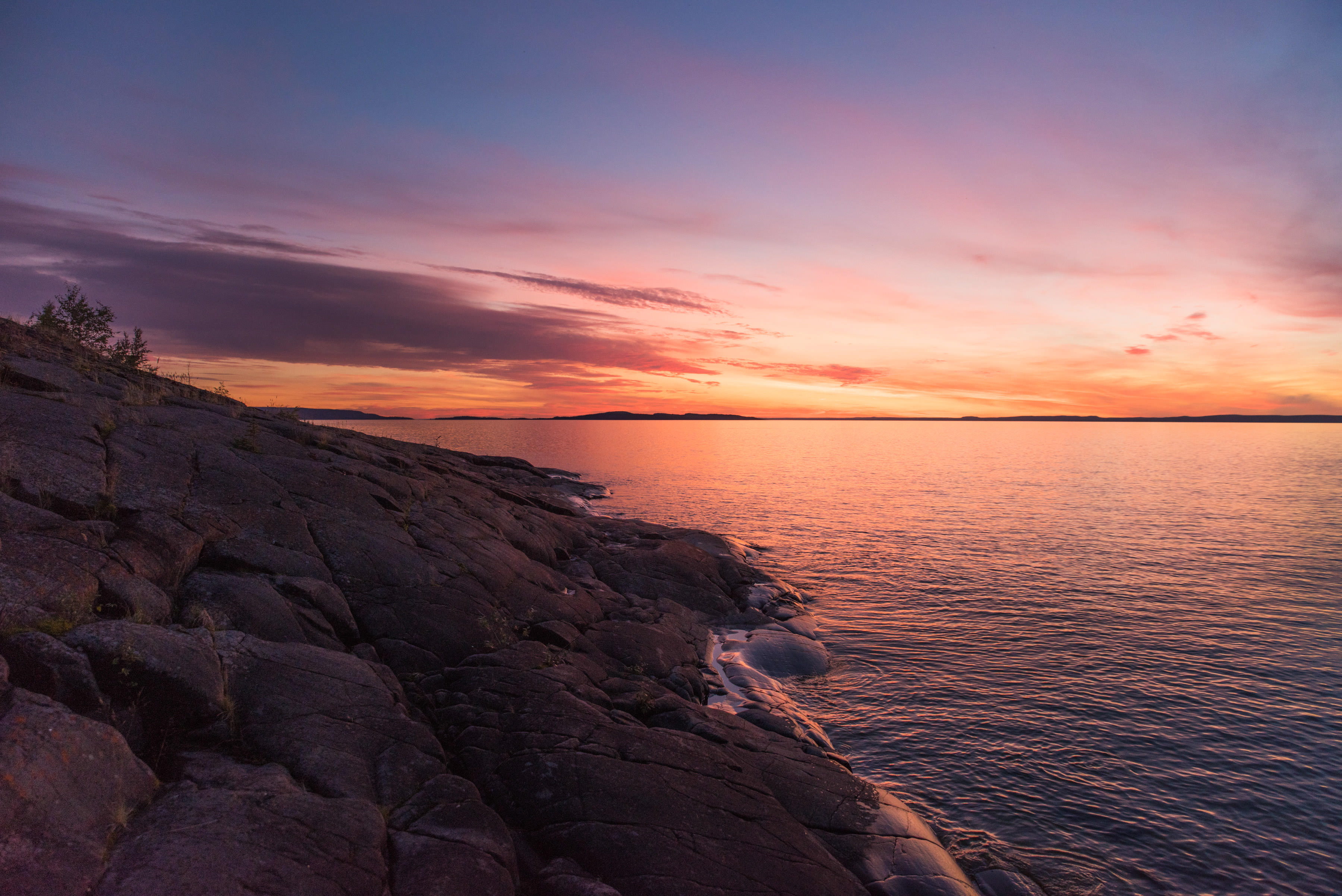 the sun sets over the rocky shoreline of great slave lake, a cold-water lake in Canada's Northwest Territories