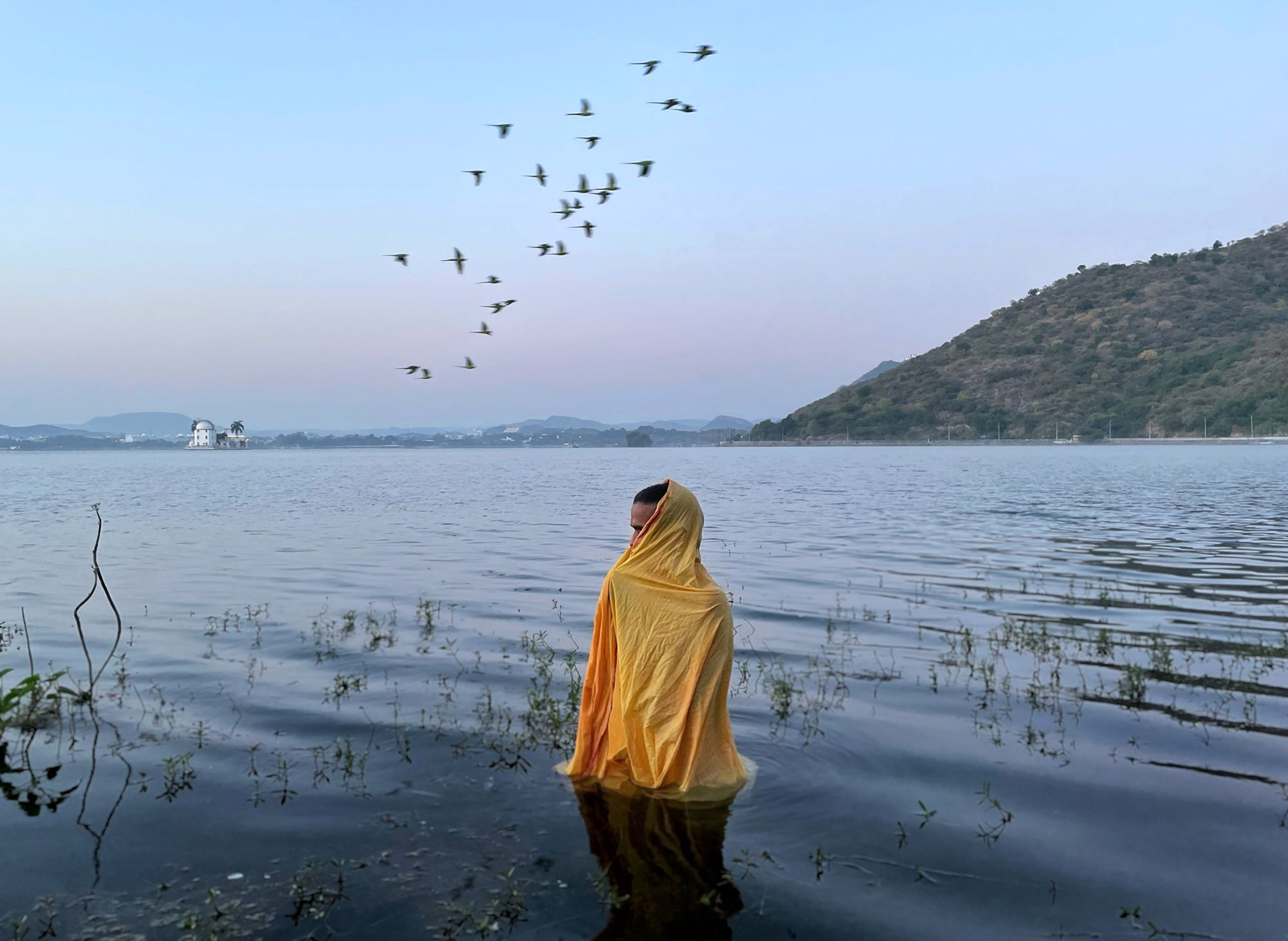 A man standing in freezing cold water waiting for Sun God to arrive during Chatth Puja Festival.