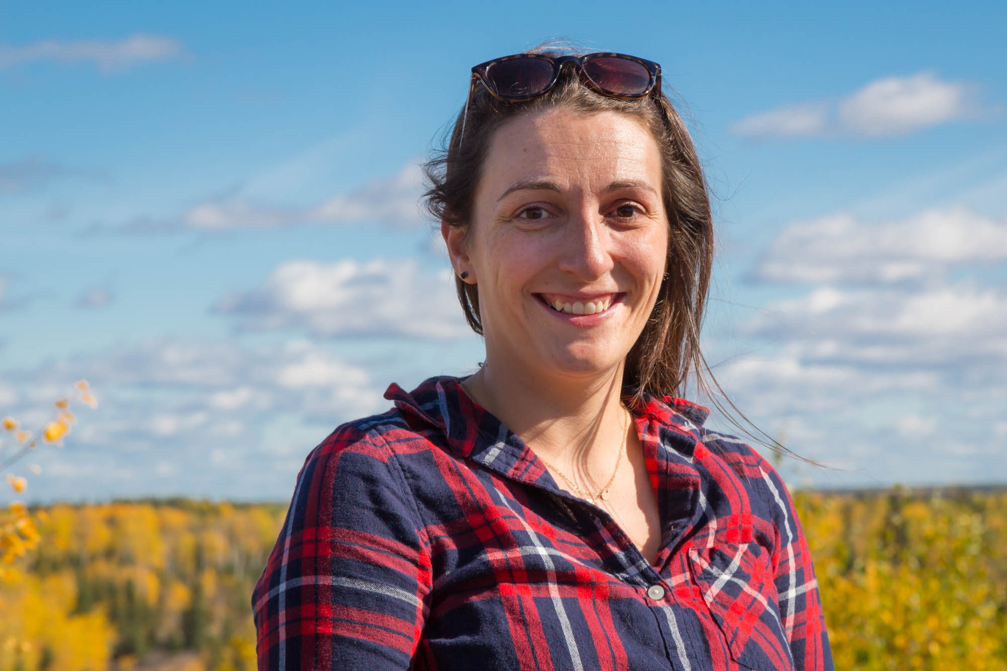 headshot of smiling woman in plaid shirt with dark hair