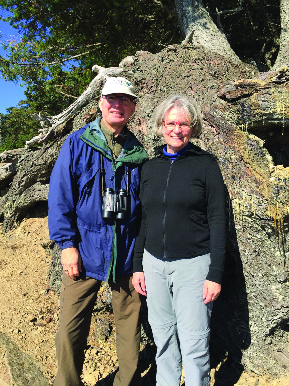 Two hikers posed in front of a tree