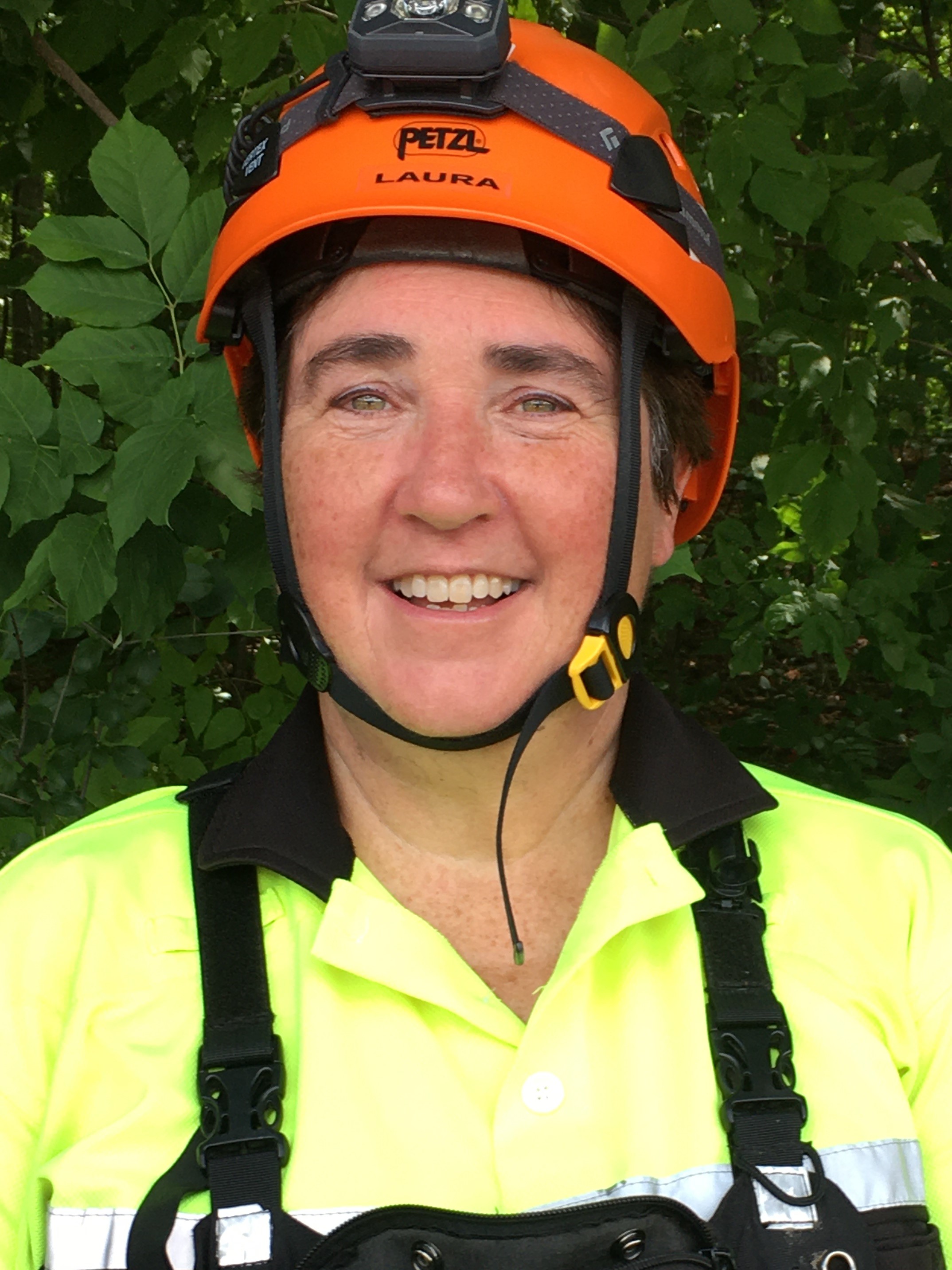 headshot of a woman in a yellow safety vest and an orange helmet