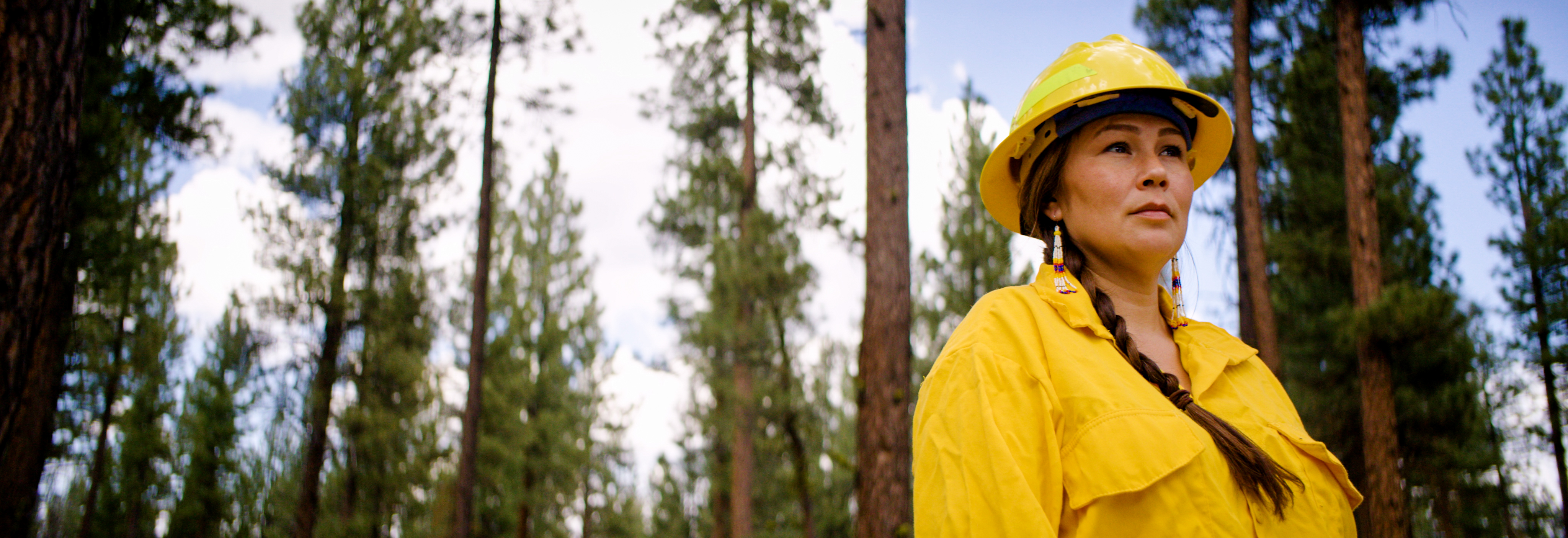 Person in hard hat standing in front of trees