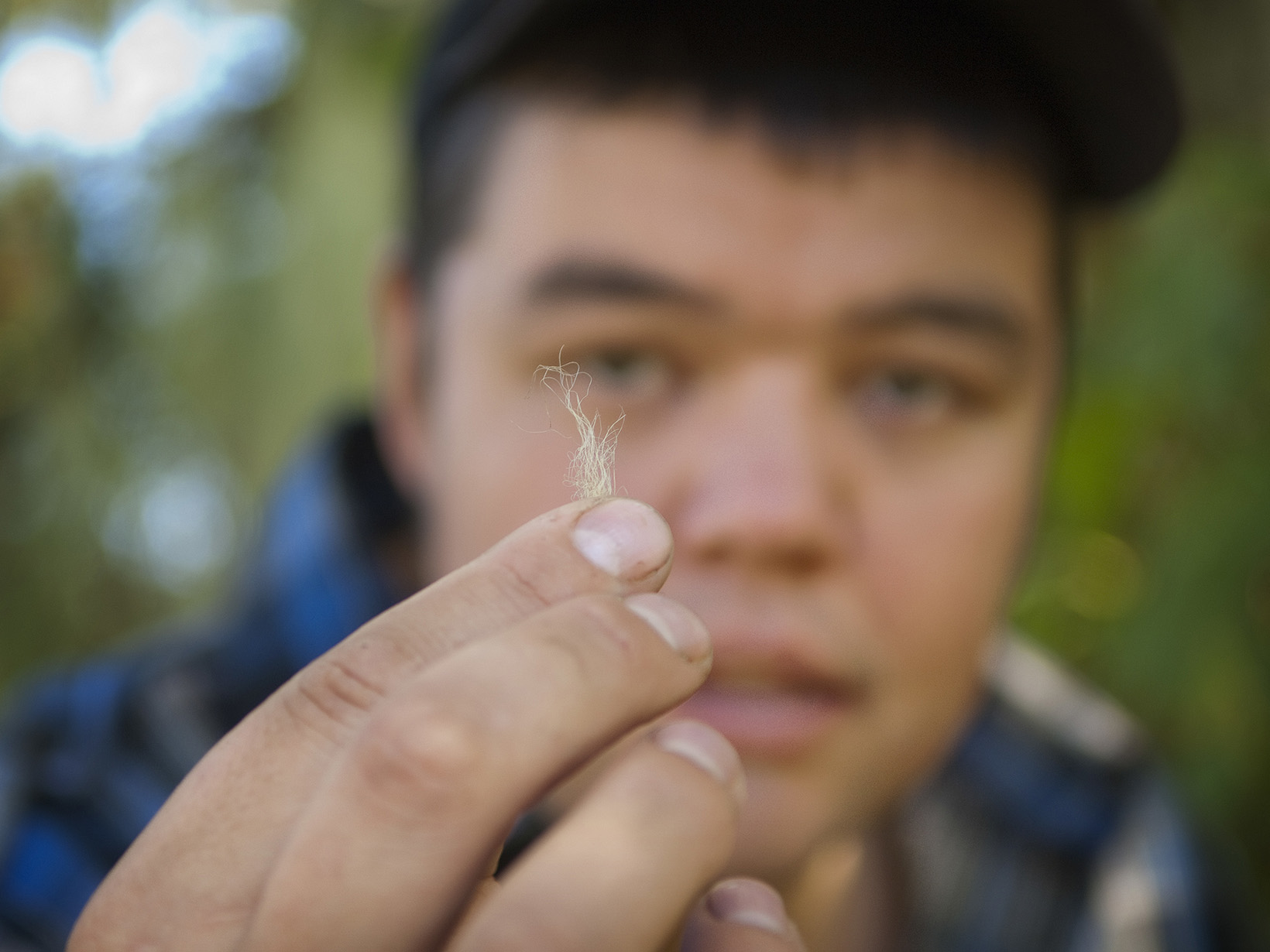 closeup of a hand with blurred man's face in the background. 